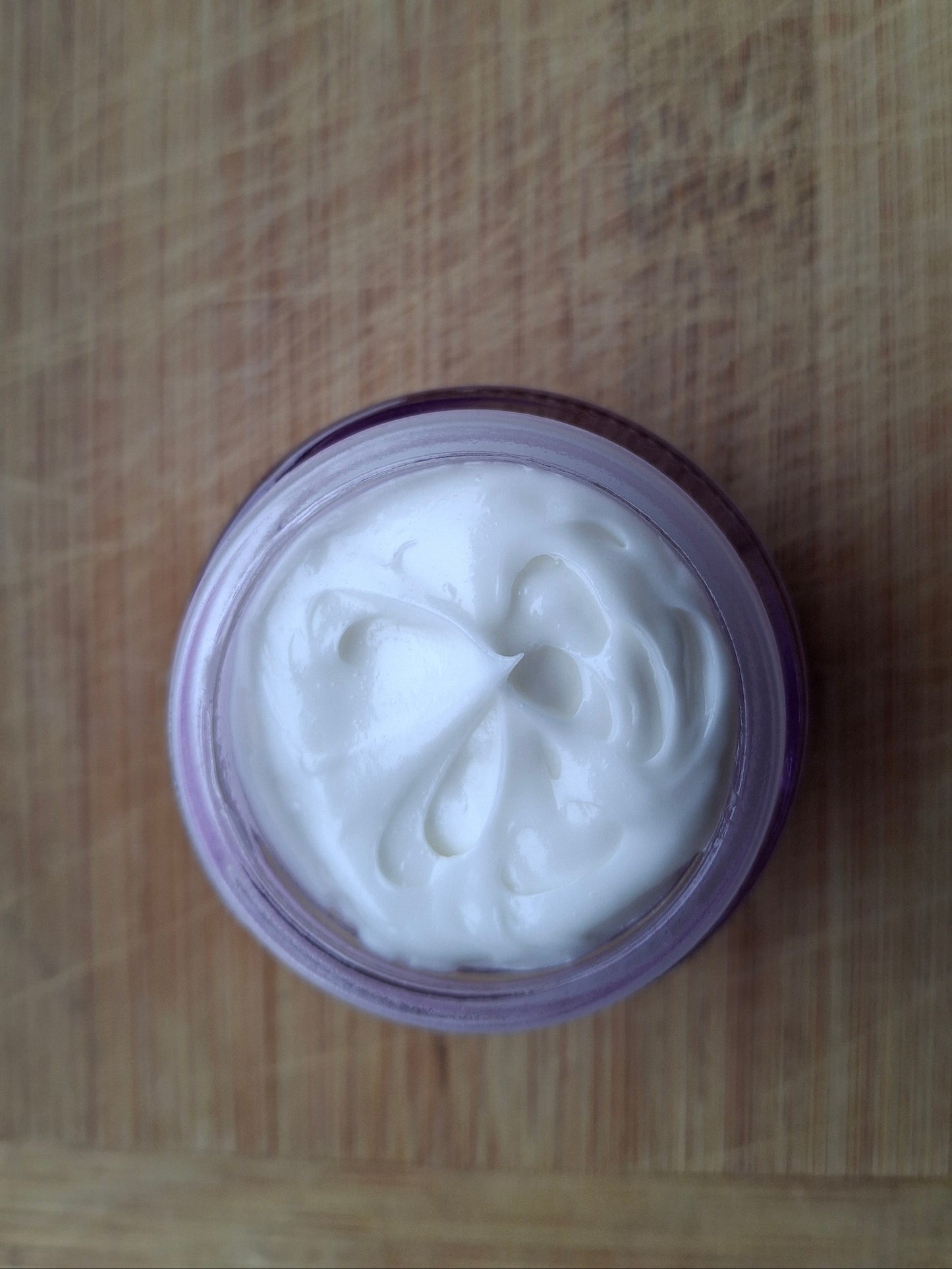 Jar of white cream on a wooden surface